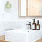Salle de bain minimaliste avec flacon d'apothicaire ambré style aesop
